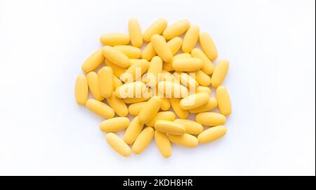 Struttura in primo piano di compresse multivitaminiche gialle su sfondo bianco. Concetto di stile di vita sano Foto Stock