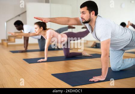 Uomo che fa l'esercitazione del cane dell'uccello con la gente in palestra Foto Stock