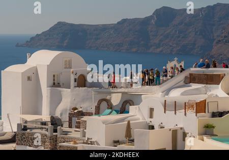 Oia, Santorini, Grecia. 2022. Turisti che scattano foto da alloggi Cliffside di fronte al mare Egeo a Oia sull'isola di Santorini, Grecia. Foto Stock