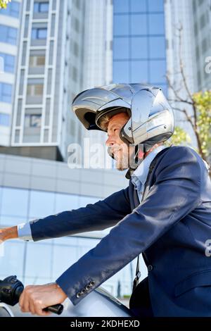 Uomo d'affari moderno in tuta mentre si siede in moto all'aperto Foto Stock