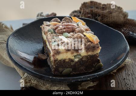 Crostini di torta al formaggio di zucca speziata fatti in casa glassa decorata con noci pecan e pistacchio affettato in piazze servito su piatto di ceramica. Foto Stock