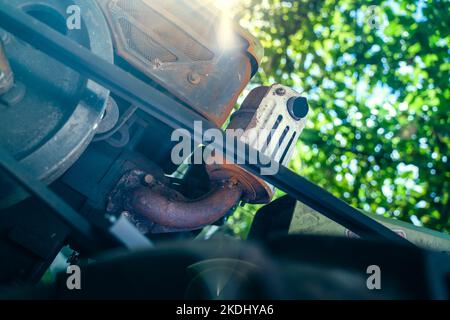 Motore diesel di un trattore retrostante con una trasmissione a cinghia in primo piano. Vista parziale dal basso con luce solare Foto Stock