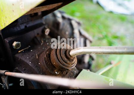 Leva di collegamento del comando della trinciatrice su un primo piano del trattore con operatore a distanza ravvicinata. Elemento di comando dell'attrezzo del trattore Foto Stock