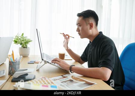 Giovane designer d'interni serio che crea un progetto per il cliente Foto Stock