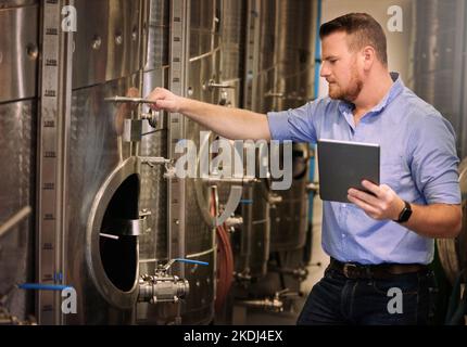 Mi piace il lato meccanico del vino, un sommelier maschile che usa la sua tavoletta digitale al lavoro. Foto Stock