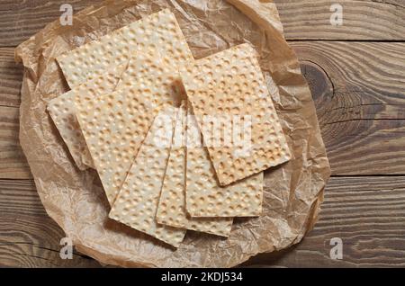 Fette di pane su carta stropicciata su vecchio tavolo di legno, vista dall'alto Foto Stock