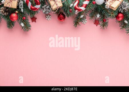 Sfondo di Natale con abete, decorazioni per le vacanze, scatole regalo su sfondo rosa. Giacitura piatta. Vista dall'alto con spazio di copia. Sfondo festivo Foto Stock