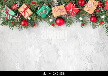 Sfondo di Natale con abete, decorazioni per le vacanze, scatole regalo su sfondo grigio cemento. Giacitura piatta. Vista dall'alto con spazio di copia. Festive backgroun Foto Stock