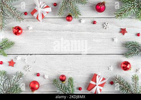 Composizione di Natale. Struttura in abete, decorazioni rosse festive, scatole regalo su fondo in legno bianco. Giacitura piatta. Vista dall'alto con spazio di copia. Vinci Foto Stock