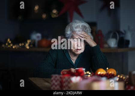 Donna anziana infelice seduta da sola e piangere durante la vigilia di Natale.concetto di solitudine anziano e salute mentale. Foto Stock