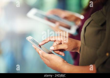 Rimanere in loop. Due persone irriconoscibili che utilizzano i loro dispositivi digitali. Foto Stock