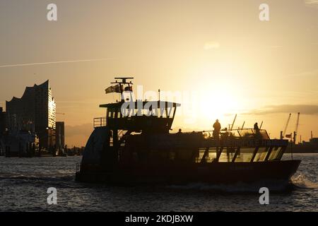 Amburgo, Germania. 07th Nov 2022. Un traghetto naviga all'alba sull'Elba nel porto di Amburgo. Sullo sfondo si vede l'Elbphilharmonie. Credit: Marcus Brandt/dpa/Alamy Live News Foto Stock