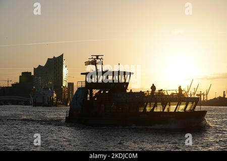 Amburgo, Germania. 07th Nov 2022. Un traghetto naviga all'alba sull'Elba nel porto di Amburgo. Sullo sfondo si vede l'Elbphilharmonie. Credit: Marcus Brandt/dpa/Alamy Live News Foto Stock