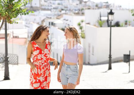 Due amici che parlano per strada in una città bianca in vacanza estiva Foto Stock