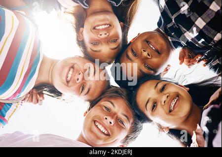 Trovano sempre un motivo per sorridere. Ritratto ad angolo basso di un gruppo di scolari diversi in piedi in una baracche. Foto Stock