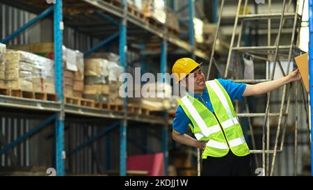 Lavoratore asiatico maschio che soffre di mal di schiena mentre si siede sulle scale in magazzino. Concetto di lavoratori industriali e industriali Foto Stock