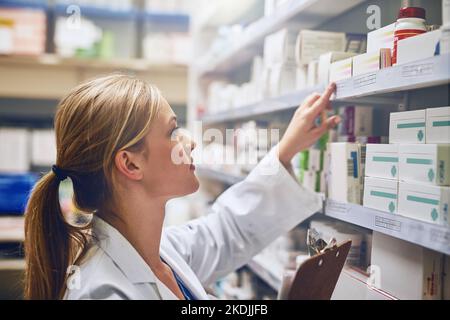 Assicurisi che tutto è nell'ordine. Un farmacista che guarda il farmaco su uno scaffale. Foto Stock