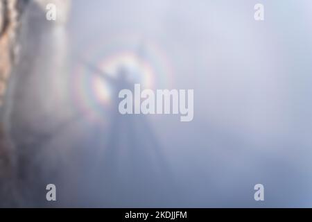 Astratto sfondo sfocato fantasma rotto alto tra le montagne sopra le onde nebbia, circondato da gloria. Silhouette su una nebbia forte e. Foto Stock