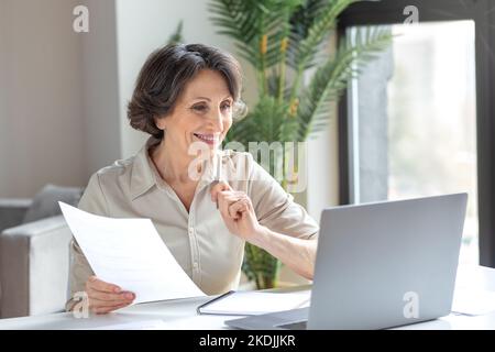 Donna d'affari sorridente che ha una videoriunione con dipendenti o partner che utilizzano un computer portatile per lavorare in remoto Foto Stock