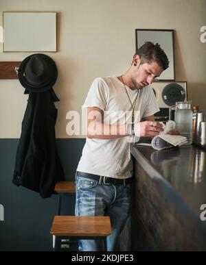 Assicurarsi che i numeri si somino. Un giovane barista attento che prende appunti sulle ricevute dietro il bar. Foto Stock