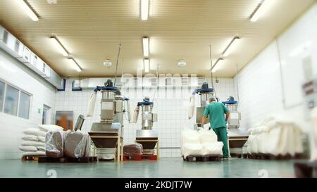 produzione, officina di fabbrica, l'operaio carica lo zucchero e la crema asciutta dai sacchetti in una macchina speciale. c'è un processo di fare il caffè istantaneo con lo zucchero e la crema,. Foto di alta qualità Foto Stock