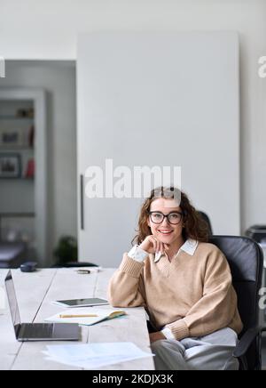 Giovane donna d'affari felice e professionale seduta alla scrivania, ritratto. Foto Stock