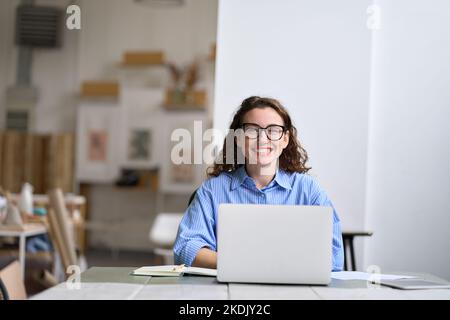 Giovane donna d'affari felice dipendente dell'azienda seduto alla scrivania che lavora su un computer portatile. Foto Stock