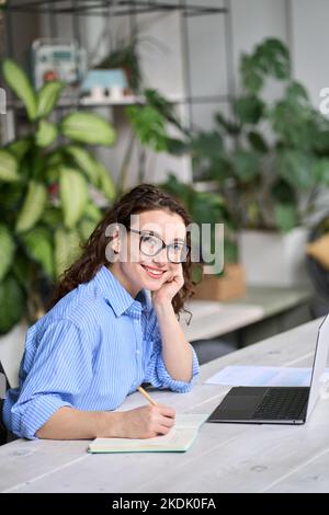 Giovane donna d'affari che lavora alla scrivania con un computer portatile. Verticale Foto Stock