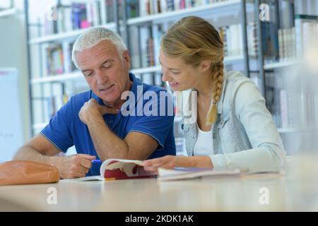 Maestro sperimentato dando lezione extra nella libreria Foto Stock