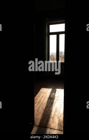 Il sole manda i suoi raggi attraverso una finestra gettando le sue ombre su un uomo meditando Foto Stock