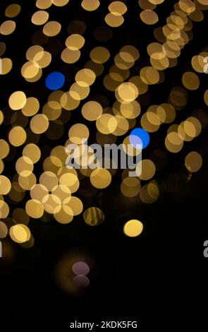 Luci di Natale sfocate da ghirlande di giallo e alcuni blu. Sfondo festivo astratto, bokeh. Colori della bandiera Ucraina Foto Stock