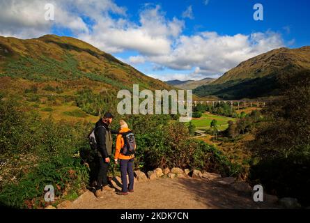 Due giovani in piedi su un punto panoramico che domina il viadotto Glenfinnan e Glen Finnan nelle Highlands a Glenfinnan, Lochaber, Scozia. Foto Stock