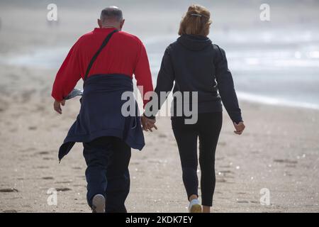 Una coppia di mezza età cammina di pari passo sulla spiaggia di A Lanzada, o Grove Foto Stock