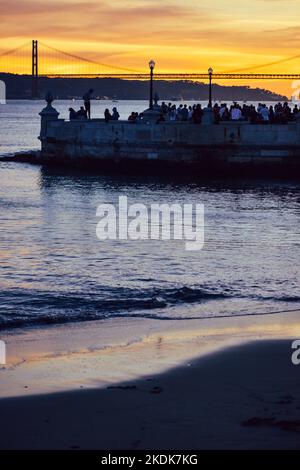 La gente gode della vista del tramonto sul fiume Tago a Lisbona Foto Stock