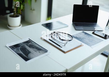 Stetoscopio, pellicola radiologica del paziente, documenti importanti e computer sulla scrivania del medico Foto Stock