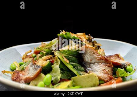 Insalata con anguilla fritta e verdure su un piatto Foto Stock