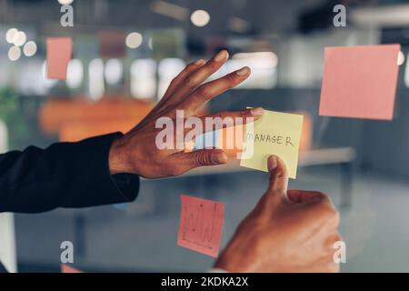 La mano della donna d'affari sta attaccando i biglietti appiccicosi sul bordo di affari in ufficio Foto Stock