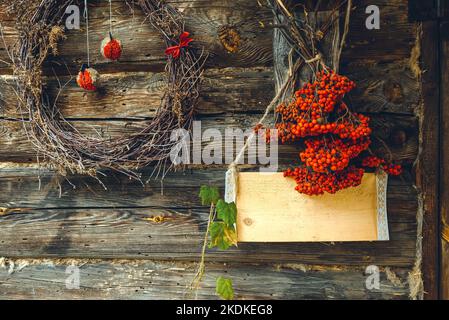 Sfondo con decorazioni natalizie su una parete di legno. I tronchi sono decorati per le vacanze. Spazio vuoto per un'iscrizione su una casa di legno Foto Stock