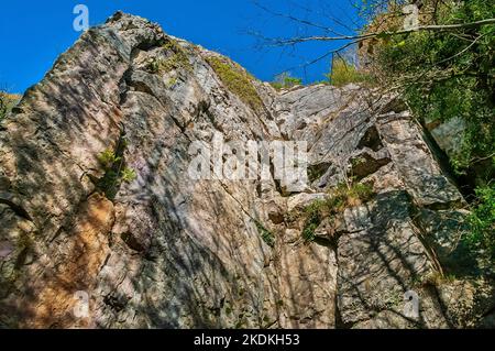 Alte scogliere calcaree, in parte arruffate, con ingressi nelle grotte e ingressi artificiali per le miniere di piombo, a Middleton Dale, Stoney Middleton, Peak District. Foto Stock