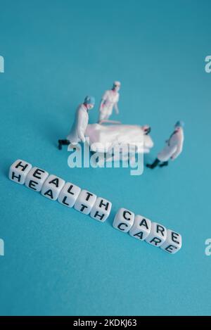 Mini giocattolo medico persone - cure mediche frasi con sfondo blu o teale Foto Stock