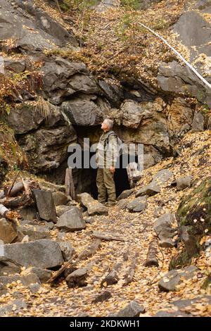 Ritratto di un uomo anziano. Un viaggio alle vecchie miniere di mica nei Monti Urali. Un turista anziano esplora le vecchie grotte abbandonate Foto Stock