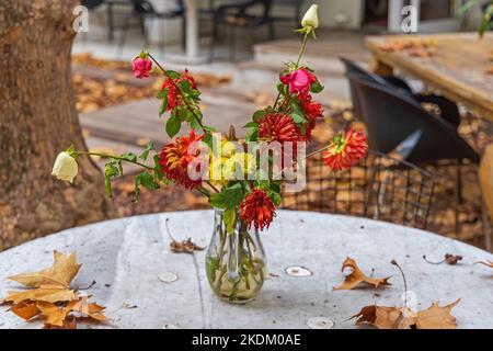 Fiori appassiti in vaso su Table Garden foglie cadute Stagione d'autunno Foto Stock
