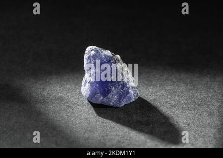 Grezza Uncut Blue e Violet Tanzanite gemma su sfondo nero. La tanzanite è la pietra preziosa Foto Stock