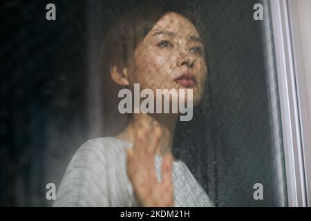Donna giapponese che guarda fuori dalla finestra Foto Stock
