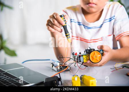 Ragazzo asiatico che monta il progetto di lavoro dell'auto robot Arduino a casa Foto Stock