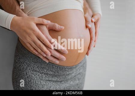 Gravidanza foto uomo e donna che tiene incinta urto in attesa di bambino. Mani di famiglia felici sul primo piano dello stomaco. Coppia innamorata. Foto Stock