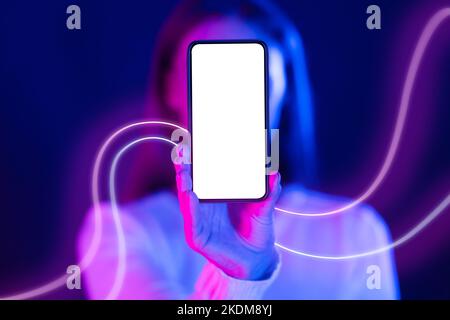 Donna irriconoscibile che si nasconde dietro il telefono cellulare con schermo vuoto, mockup Foto Stock