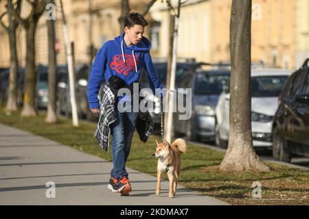 Giovane uomo che cammina il suo cane in Piazza del Re Tomislav (Trg Kralja Tomislava) durante l'inverno. Zagabria, Croazia Foto Stock