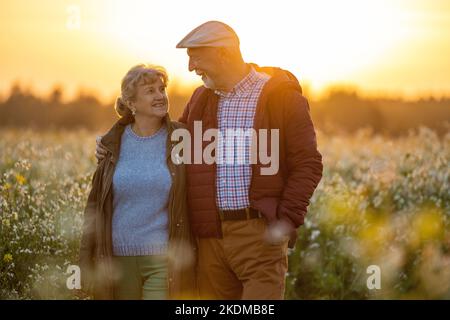 Coppia anziana in un campo in autunno al tramonto Foto Stock