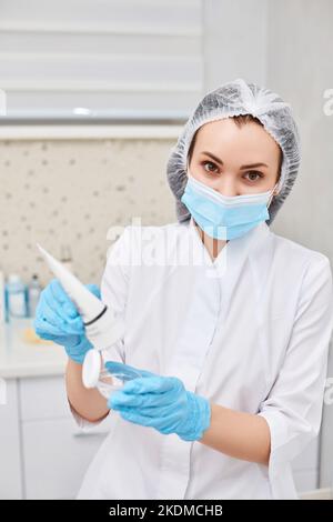 vasetto di crema in mani di estetista Foto Stock